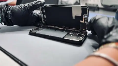 Technicien NomoPhone ouvrant un iPhone sur l’établi de l’atelier